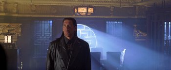 Movie still from “The Replacement Killers” (1998), directed by Antoine Fuqua – A man standing in front of a projection of a nazi symbol; Medium shot, Low angle