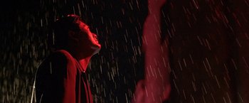 Movie still from “The Replacement Killers” (1998), directed by Antoine Fuqua – A man standing in the rain looking up at the sky; Medium shot, Low angle