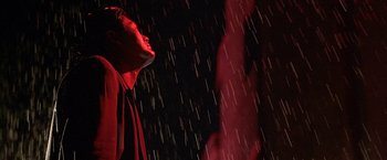 Movie still from “The Replacement Killers” (1998), directed by Antoine Fuqua – A man standing in the rain wearing a red jacket; Close Up shot, Low angle