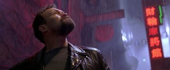 Movie still from “The Replacement Killers” (1998), directed by Antoine Fuqua – A man with a beard is standing in the rain; Close Up shot, Low angle