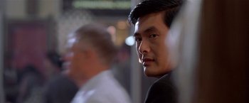 Movie still from “The Replacement Killers” (1998), directed by Antoine Fuqua – A person wearing a suit and tie; Close Up shot, Over the shoulder angle