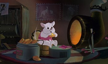 Movie still from “The Rescuers Down Under” (1990), directed by Mike Gabriel – A mouse sitting on top of a barrel in a room; Wide shot, High angle