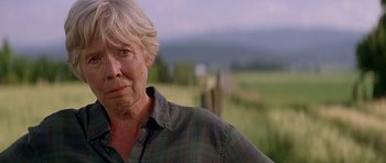Movie still from “The River Wild” (1994), directed by Curtis Hanson – An older woman standing in front of a field; Close Up shot, Low angle