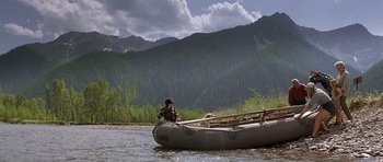 Movie still from “The River Wild” (1994), directed by Curtis Hanson – A person in a boat on a river with mountains in the background; Wide shot, Low angle
