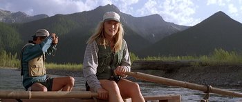Movie still from “The River Wild” (1994), directed by Curtis Hanson – A woman sitting on a wooden railing in the water; Medium shot, High angle