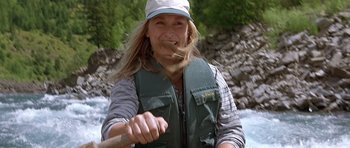 Movie still from “The River Wild” (1994), directed by Curtis Hanson – A woman is holding a stick in her mouth while paddling a canoe; Close Up shot, High angle