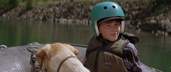 Movie still from “The River Wild” (1994), directed by Curtis Hanson – A young boy wearing a helmet while sitting on a boat; Close Up shot, Over the shoulder angle