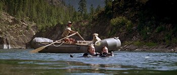 Movie still from “The River Wild” (1994), directed by Curtis Hanson – Two people and a dog are in the water while a boat is in the water; Wide shot, High angle