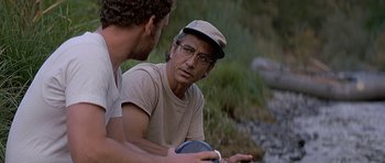 Movie still from “The River Wild” (1994), directed by Curtis Hanson – A man wearing glasses and a hat talking to another man; Close Up shot, Over the shoulder angle