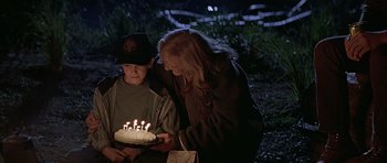 Movie still from “The River Wild” (1994), directed by Curtis Hanson – A woman and a boy with a birthday cake; Medium shot, High angle