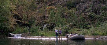Movie still from “The River Wild” (1994), directed by Curtis Hanson – A man and a woman standing in the water; Extreme Wide shot, High angle
