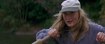 Movie still from “The River Wild” (1994), directed by Curtis Hanson – A woman holding a baseball bat while wearing a hat; Close Up shot, Over the shoulder angle