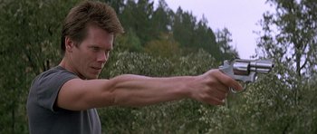 Movie still from “The River Wild” (1994), directed by Curtis Hanson – A man holding a gun in his hand; Close Up shot, Low angle