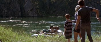 Movie still from “The River Wild” (1994), directed by Curtis Hanson – A boy standing next to an inflatable raft on a river; Wide shot, Over the shoulder angle