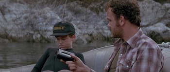 Movie still from “The River Wild” (1994), directed by Curtis Hanson – A man and a young boy looking at a book; Medium shot, High angle
