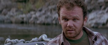 Movie still from “The River Wild” (1994), directed by Curtis Hanson – A person wearing a plaid shirt near a body of water; Close Up shot, Low angle