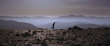 Movie still from “The River Wild” (1994), directed by Curtis Hanson – A man running on a rocky mountain side; Extreme Wide shot, High angle