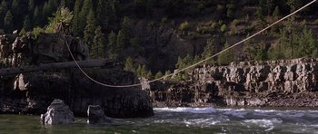 Movie still from “The River Wild” (1994), directed by Curtis Hanson – A rope hanging over a body of water near a cliff; Extreme Wide shot, High angle