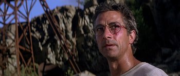 Movie still from “The River Wild” (1994), directed by Curtis Hanson – A person wearing glasses with a mountain in the background; Close Up shot, Low angle