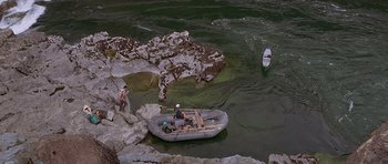Movie still from “The River Wild” (1994), directed by Curtis Hanson – Two people in a boat in a body of water; Extreme Wide shot, High angle