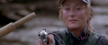 Movie still from “The River Wild” (1994), directed by Curtis Hanson – A woman holding a gun in her right hand; Close Up shot, Over the shoulder angle