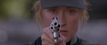Movie still from “The River Wild” (1994), directed by Curtis Hanson – A woman is holding a gun in her hand; Close Up shot, Low angle
