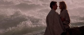 Movie still from “The River Wild” (1994), directed by Curtis Hanson – Two people wrapped in a blanket near the ocean; Medium shot, Over the shoulder angle