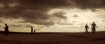 Movie still from “The Rookie” (2002), directed by John Lee Hancock – Two people walking in a field under a cloudy sky; Extreme Wide shot, Low angle