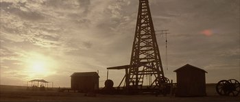 Movie still from “The Rookie” (2002), directed by John Lee Hancock – An oil rig is shown in silhouette against a cloudy sky; Extreme Wide shot, Low angle