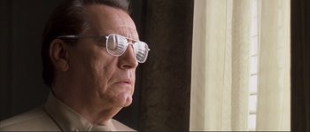 Movie still from “The Rookie” (2002), directed by John Lee Hancock – An older man wearing glasses looking out of a window; Close Up shot, Low angle