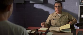Movie still from “The Rookie” (2002), directed by John Lee Hancock – A man sitting at a table in front of papers; Medium shot, Over the shoulder angle