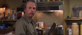 Movie still from “The Rookie” (2002), directed by John Lee Hancock – A man with a beard and mustache holding an object in his hand; Close Up shot, Low angle