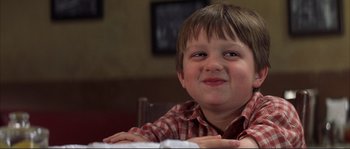 Movie still from “The Rookie” (2002), directed by John Lee Hancock – A young boy sitting at a table with his arms crossed; Close Up shot, Low angle