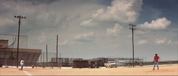 Movie still from “The Rookie” (2002), directed by John Lee Hancock – A truck parked in front of a fence with power lines in the background; Extreme Wide shot, Low angle