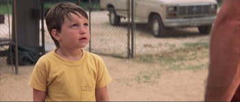 Movie still from “The Rookie” (2002), directed by John Lee Hancock – A young boy in a yellow t - shirt looking up; Close Up shot, Low angle