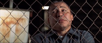 Movie still from “The Rookie” (2002), directed by John Lee Hancock – A man looking through a chain link fence; Close Up shot, Low angle