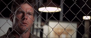 Movie still from “The Rookie” (2002), directed by John Lee Hancock – A man standing in front of a chain link fence; Close Up shot, Low angle