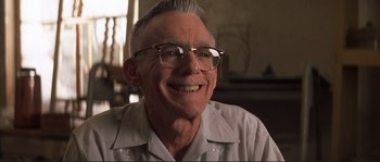 Movie still from “The Rookie” (2002), directed by John Lee Hancock – An older man wearing glasses and smiling for the camera; Close Up shot, Low angle