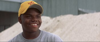 Movie still from “The Rookie” (2002), directed by John Lee Hancock – A young man wearing a hat and smiling for the camera; Close Up shot, Low angle
