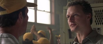 Movie still from “The Rookie” (2002), directed by John Lee Hancock – A man in a yellow shirt is looking at the camera; Close Up shot, Over the shoulder angle