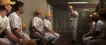 Movie still from “The Rookie” (2002), directed by John Lee Hancock – A group of baseball players sitting on a bench in a locker room; Wide shot, Over the shoulder angle