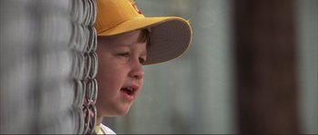 Movie still from “The Rookie” (2002), directed by John Lee Hancock – A little boy wearing a yellow hat and white shirt; Close Up shot, Low angle