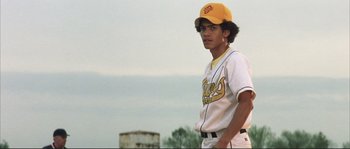 Movie still from “The Rookie” (2002), directed by John Lee Hancock – A young baseball player in a yellow cap and uniform; Medium shot, Low angle