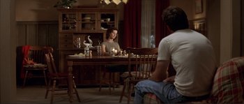 Movie still from “The Rookie” (2002), directed by John Lee Hancock – A woman sitting at a dining room table with candles; Wide shot, Over the shoulder angle