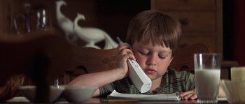 Movie still from “The Rookie” (2002), directed by John Lee Hancock – A young boy holding a phone up to his ear; Medium shot, Low angle