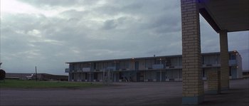 Movie still from “The Rookie” (2002), directed by John Lee Hancock – A motel with a parking lot in front of it; Extreme Wide shot, Low angle