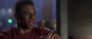 Movie still from “The Rookie” (2002), directed by John Lee Hancock – A person sitting at a table holding a glass; Close Up shot, Low angle