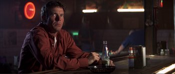 Movie still from “The Rookie” (2002), directed by John Lee Hancock – A man sitting at a table with a bottle of soda; Close Up shot, Low angle
