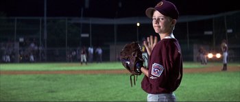 Movie still from “The Rookie” (2002), directed by John Lee Hancock – A young baseball player holding a catchers mitt on a baseball field at night; Medium shot, Low angle
