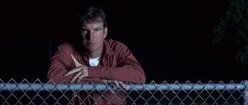 Movie still from “The Rookie” (2002), directed by John Lee Hancock – A man leaning on a fence with his arms crossed; Close Up shot, Low angle